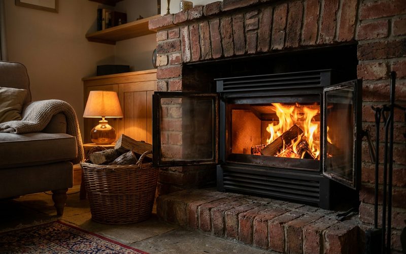 Modern black wood-burning fireplace insert in a brick hearth with a cheerful fire