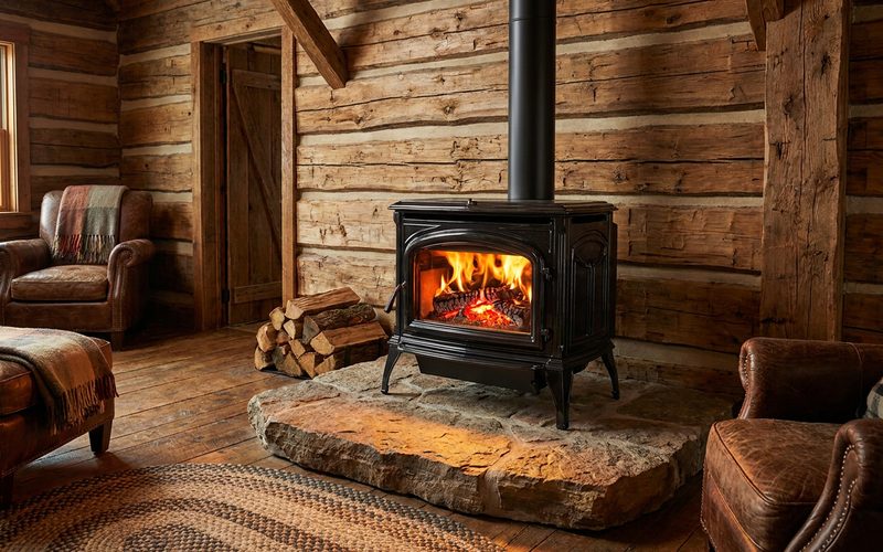 Glowing cast iron wood stove with a kettle on top in a log cabin corner